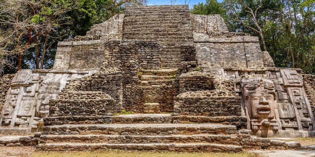 Ancient Maya pyramid with carved stone mask at the Lamanai archaeological site, Belize