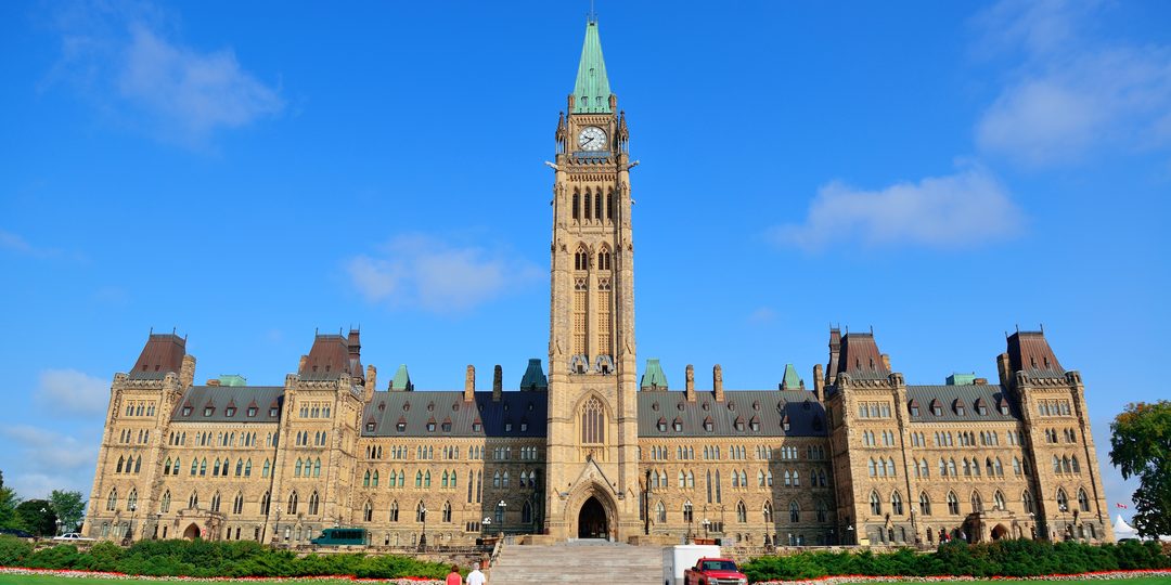 Parliament Hill's Peace Tower and Gothic Revival buildings under a clear blue sky in Ottawa.