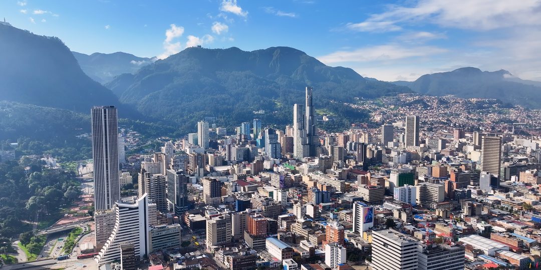 Aerial view of downtown Bogotá's skyscrapers with the Andes mountains rising behind the city.