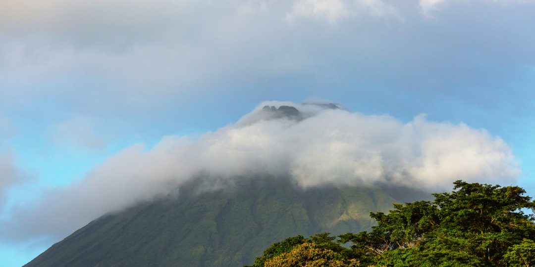 Arenal Volcano's cloud wrapped peak rising above the rainforest canopy in Costa Rica.