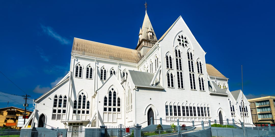 White wooden Gothic Revival cathedral against a blue sky in Georgetown, Guyana