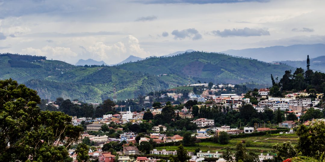 Aerial view of a city nestled among green mountains under a cloudy sky