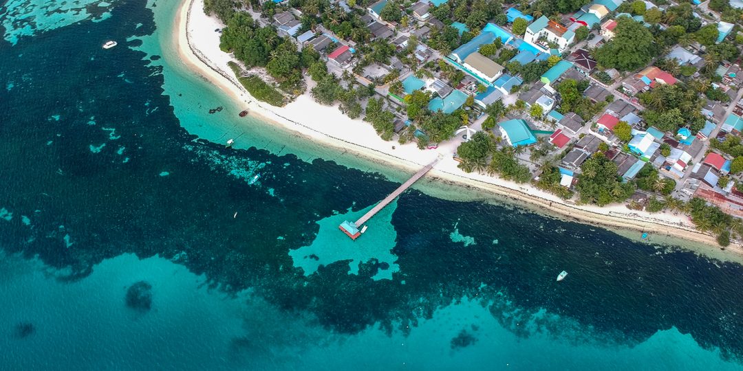 Aerial view of a turquoise reef and coastal village