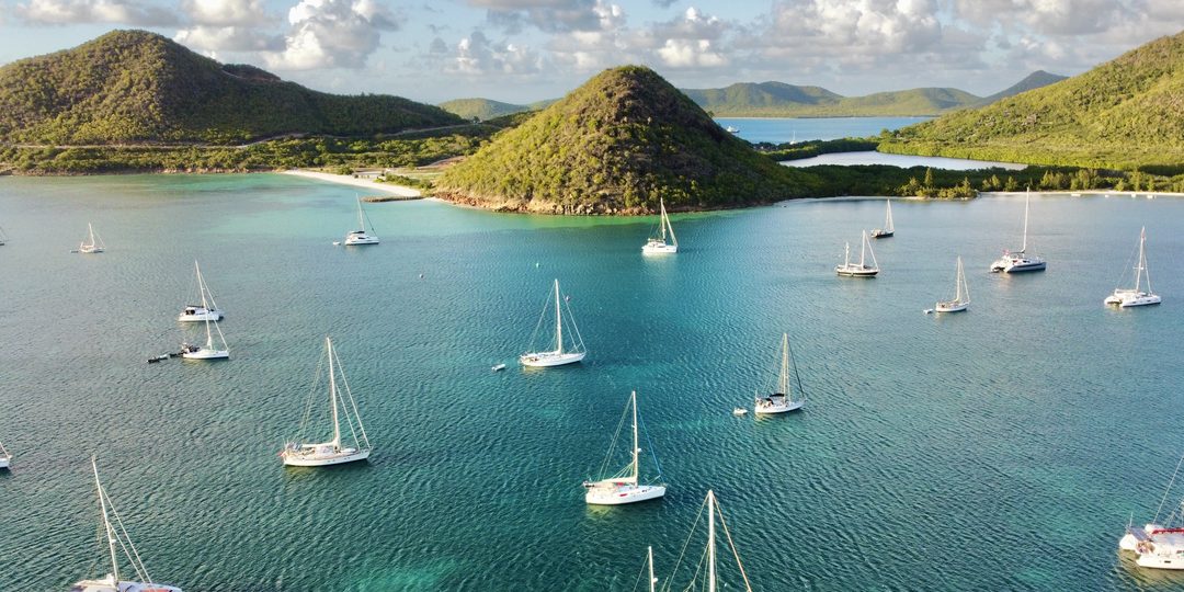 Sailboats anchored in a turquoise bay among green hills