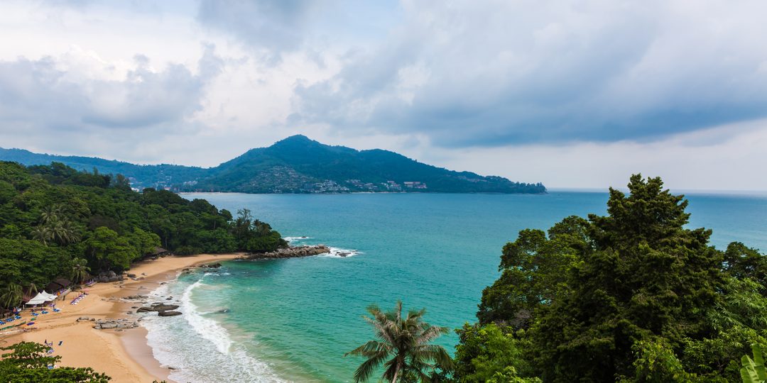 Aerial view of a palm-fringed crescent beach and turquoise bay