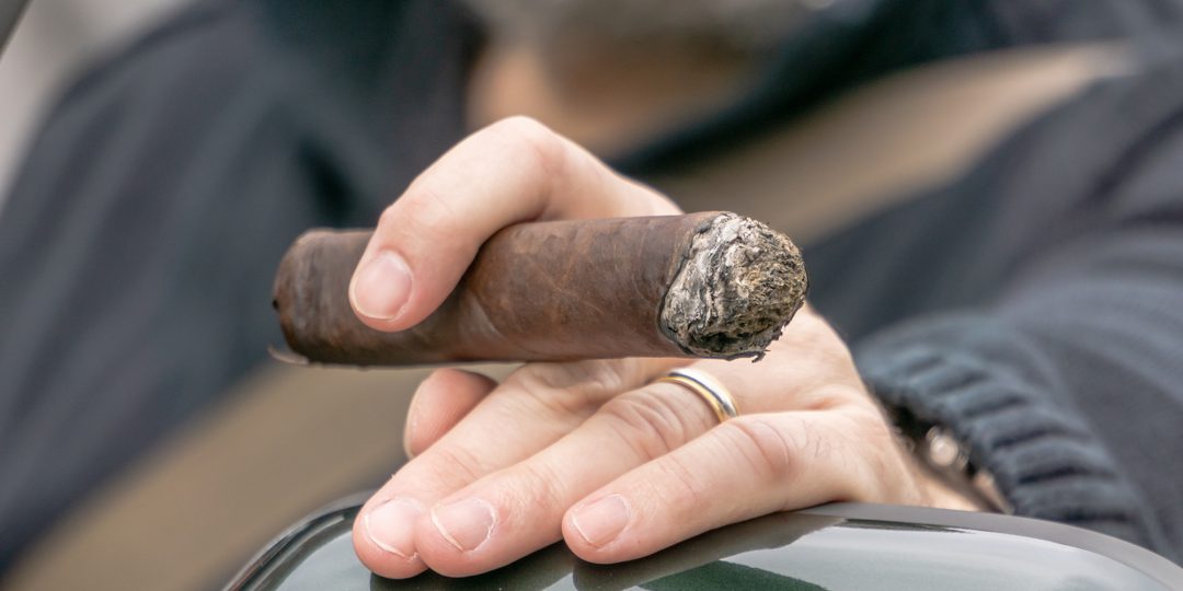 Close up of a hand holding a hand rolled cigar.