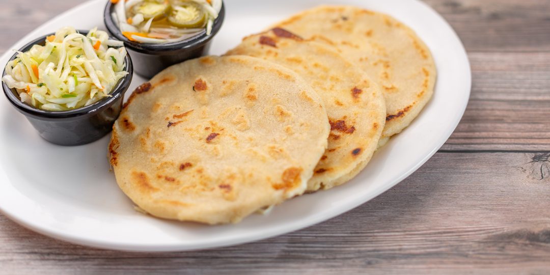 A plate of grilled pupusas served with curtido and salsa