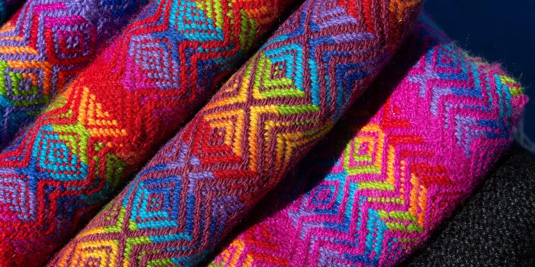 Close-up of brightly colored handwoven textile with geometric diamond patterns