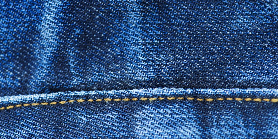 Close-up of blue denim jean fabric with stitched seam
