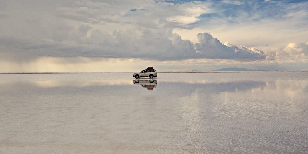 Off-road vehicle reflected on the flooded Salar de Uyuni salt flat, Bolivia