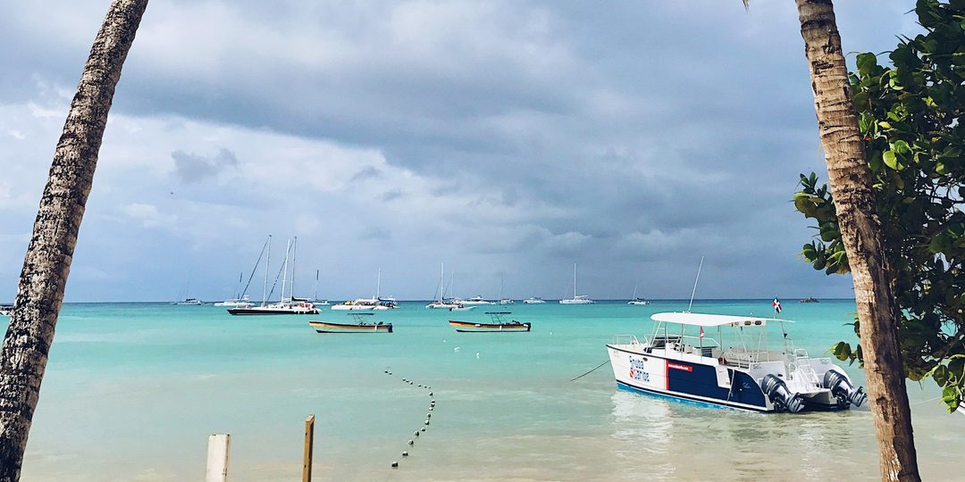 Palm trees framing a turquoise bay with anchored boats in Punta Cana
