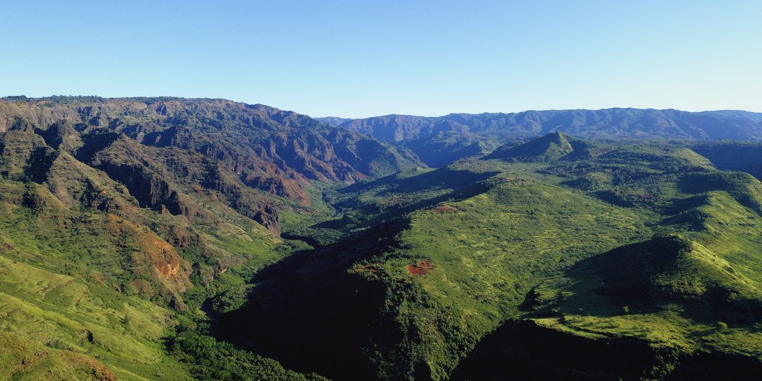 Aerial view of a lush green mountain valley under a blue sky